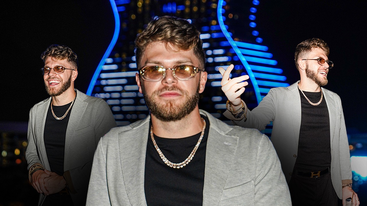 Christian Barker (Bark) in a grey blazer and gold chain at a night event